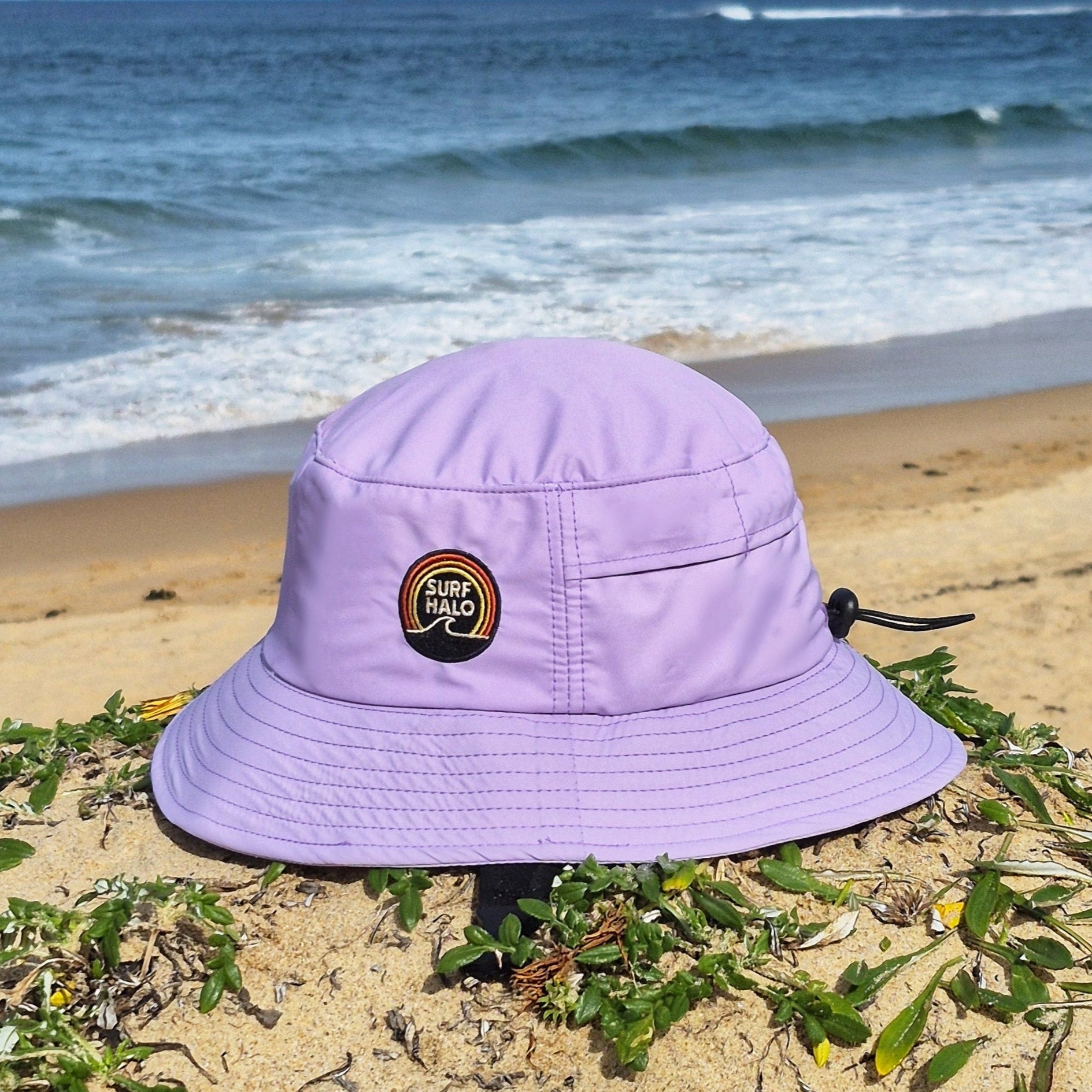purple lilac surf hat bucket style with UPF 50+ and wide brim on a beach