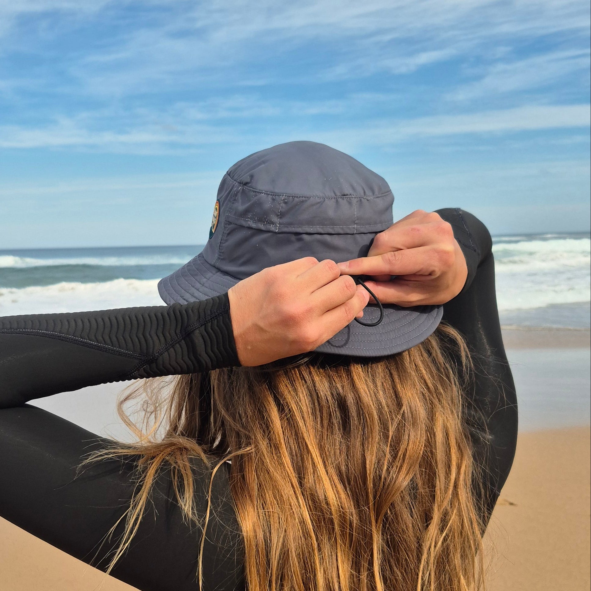 Person with long hair wearing a black outfit against a blue sky background